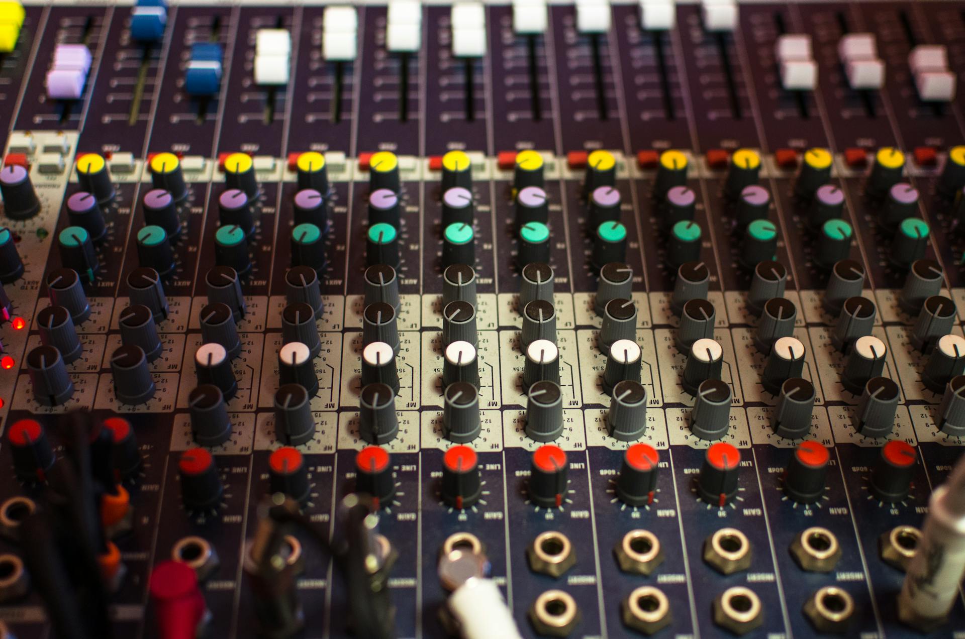 Sound mixing console with colorful faders and knobs in a professional studio