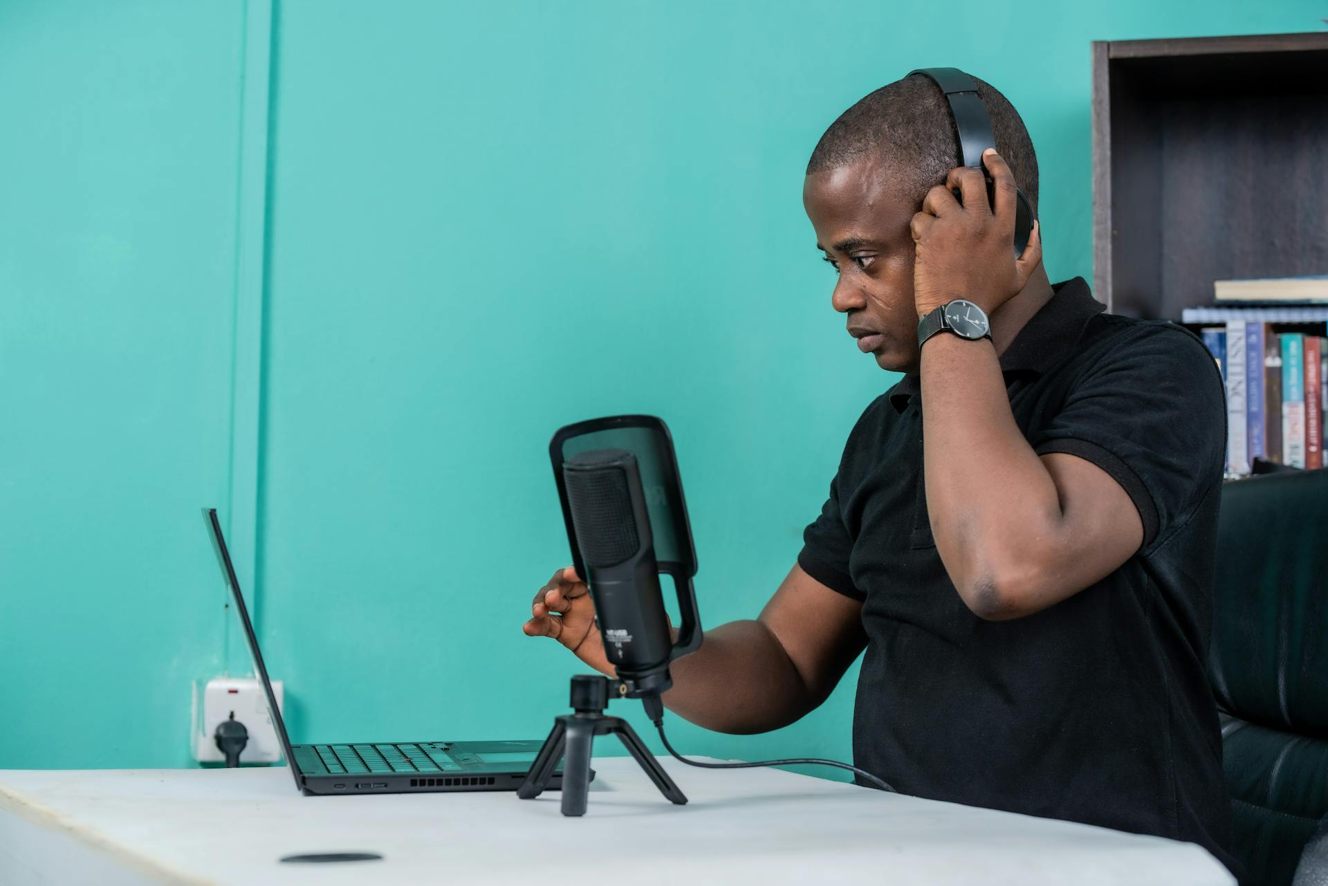 Person editing audio on a laptop with headphones and waveform visualization