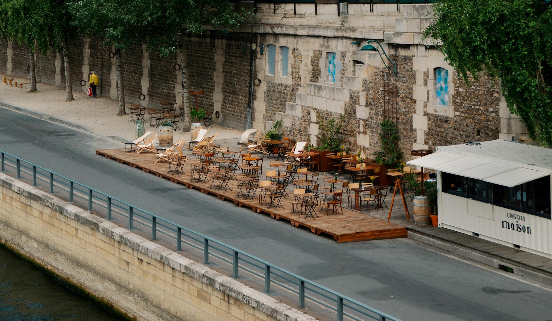 Outdoor riverside café terrace in Paris, France with people dining along the Seine