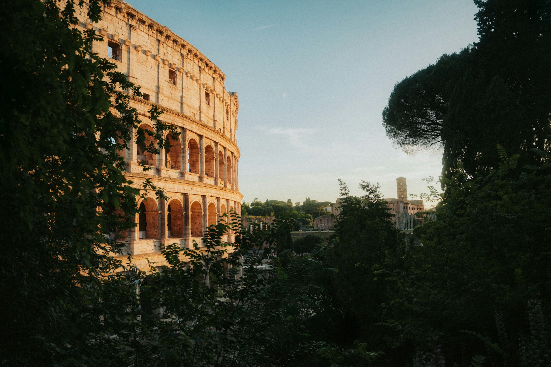 The Colosseum stands tall in the Roman landscape against a clear blue sky
