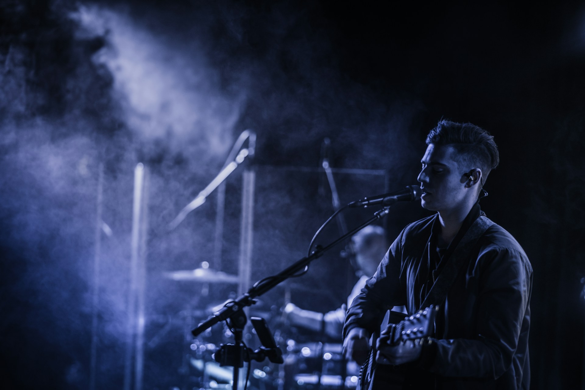 A musician performing on stage with a guitar, lit by warm stage lighting